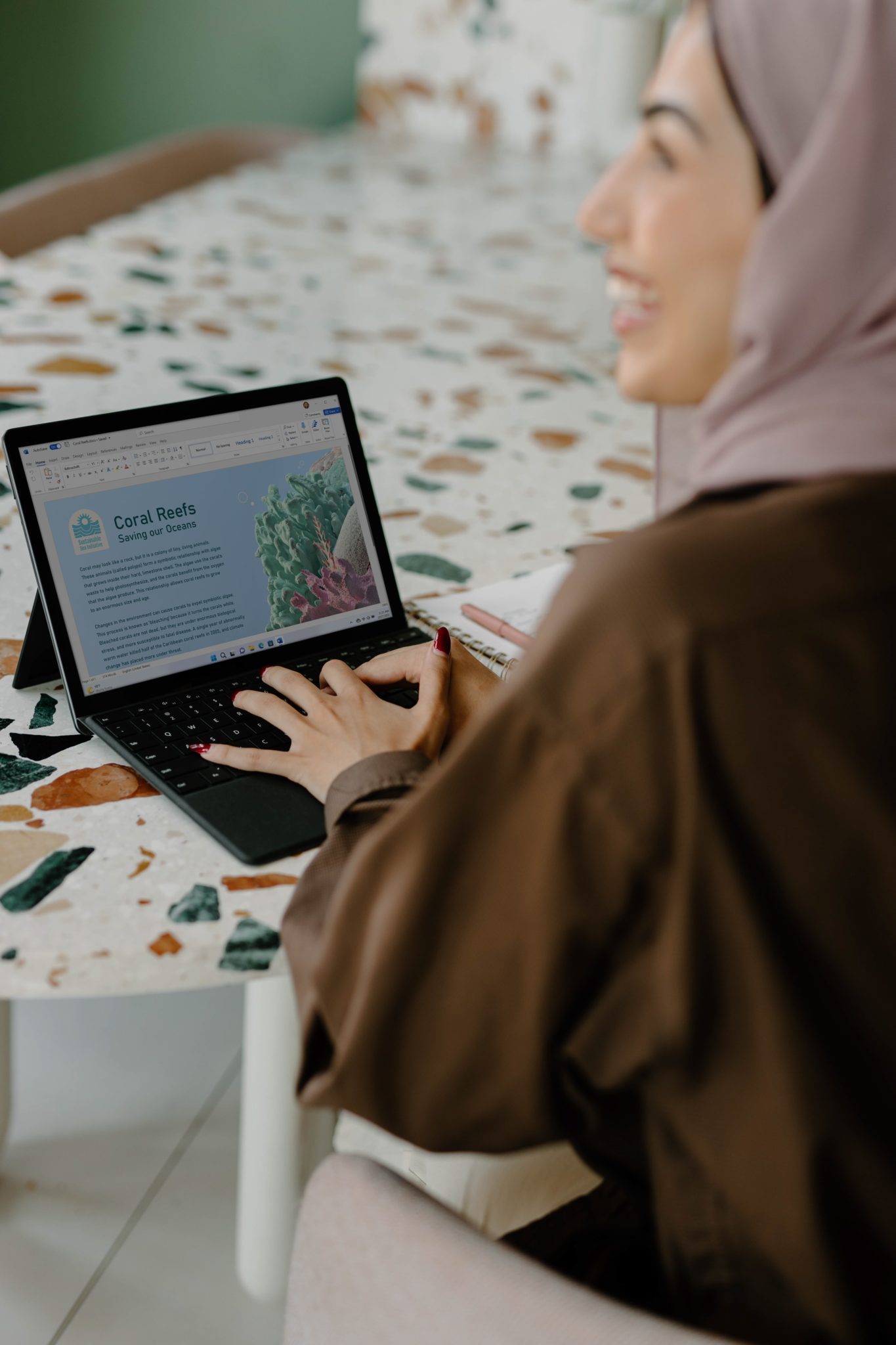A Conservation Communicator typing on her laptop, which shows a page about coral reefs.