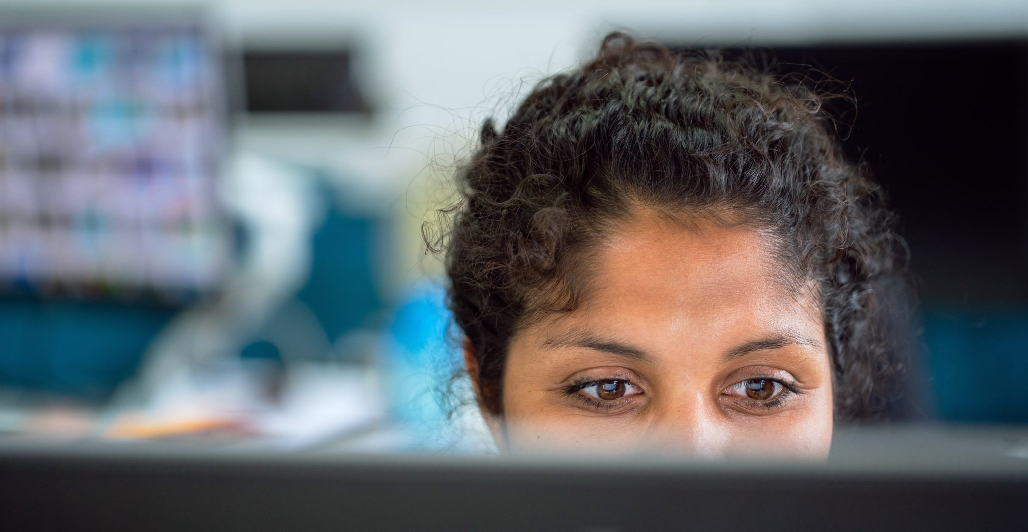 A conservation communicator sits behind her computer screen in an office environment.