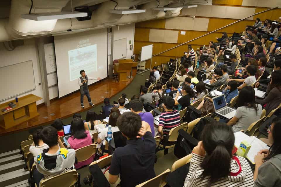 Stan stands in a lecture hall, giving a lecture to students about overfishing and over consumption.