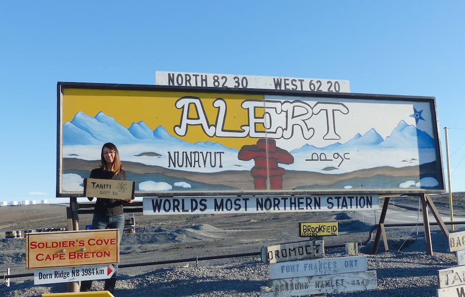 Dr. Sandra Lai standing in front of the World’s most Northern station Alert signposts on Ellesmere Island in Canada.