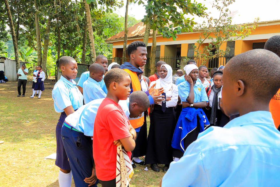 Julius educating a group of high school students in an outdoor setting, discussing the importance of sustainable practices.