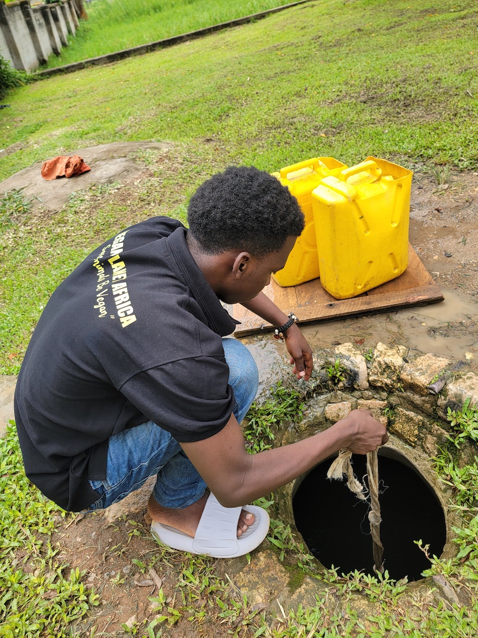 Julius drawing water from a well at Winterland Primary School to assist in preparing plant-based meals for students during a community project.