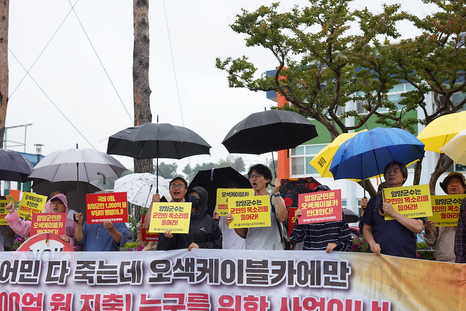 Yongki stands with other campaigners holding placards in the rain.