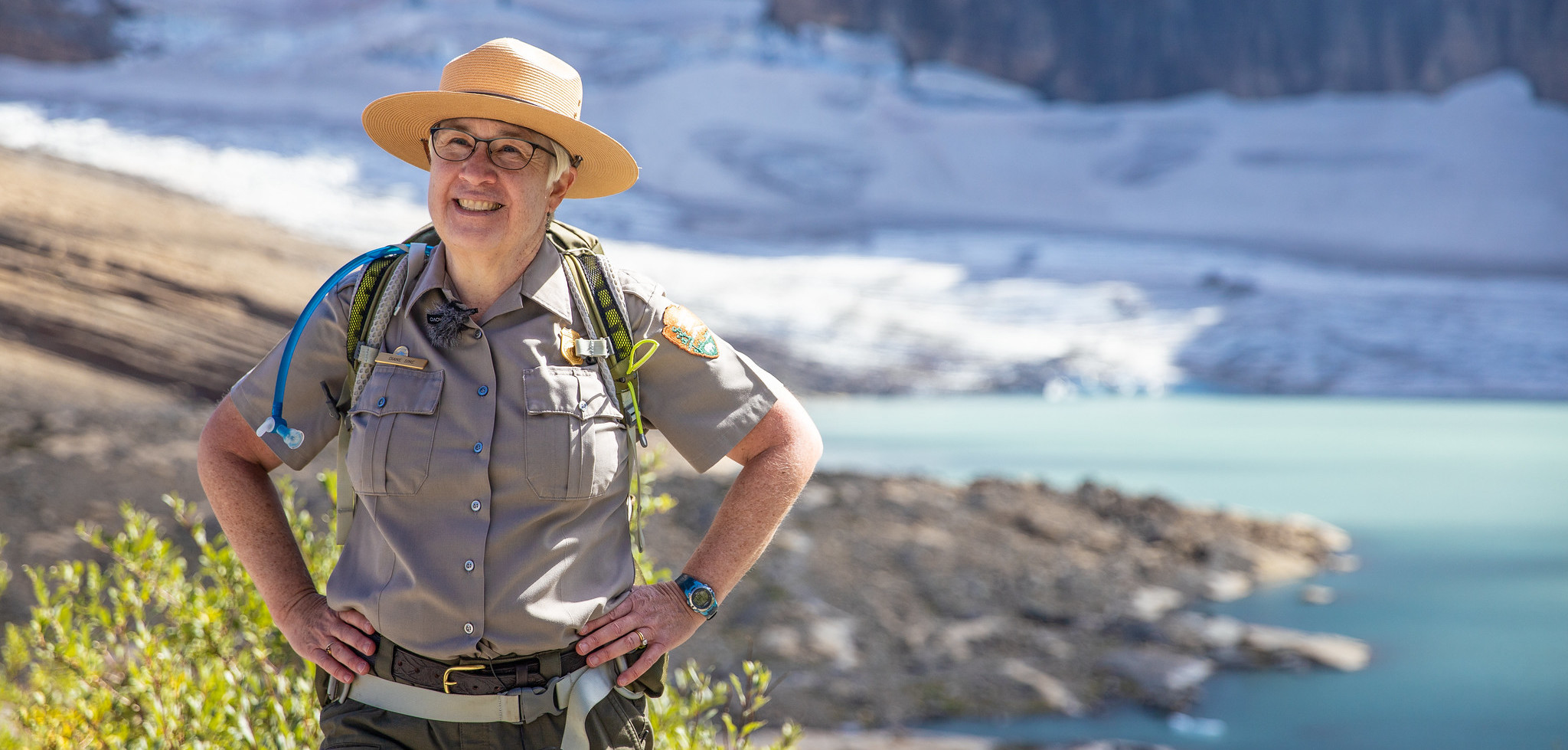 A forest ranger standing in front of a glacier.