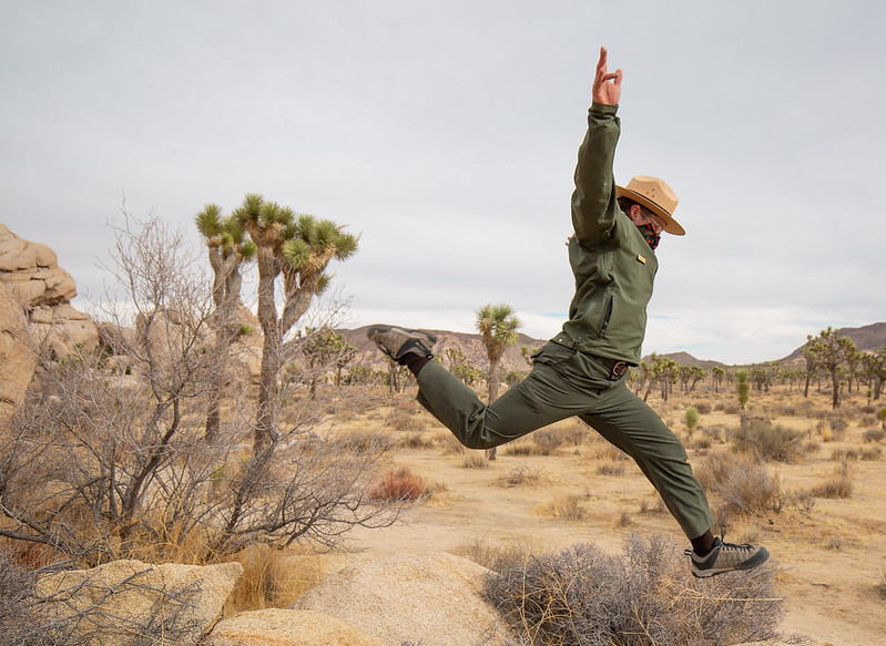 A forest ranger in uniform jumping in an arid landscape. Learn how to become a forest ranger in this ultimate guide and have fun in your career!