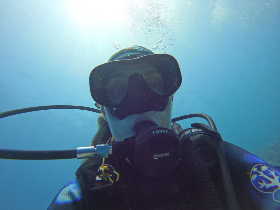 A woman diving under the water surface and looking directly at the camera.