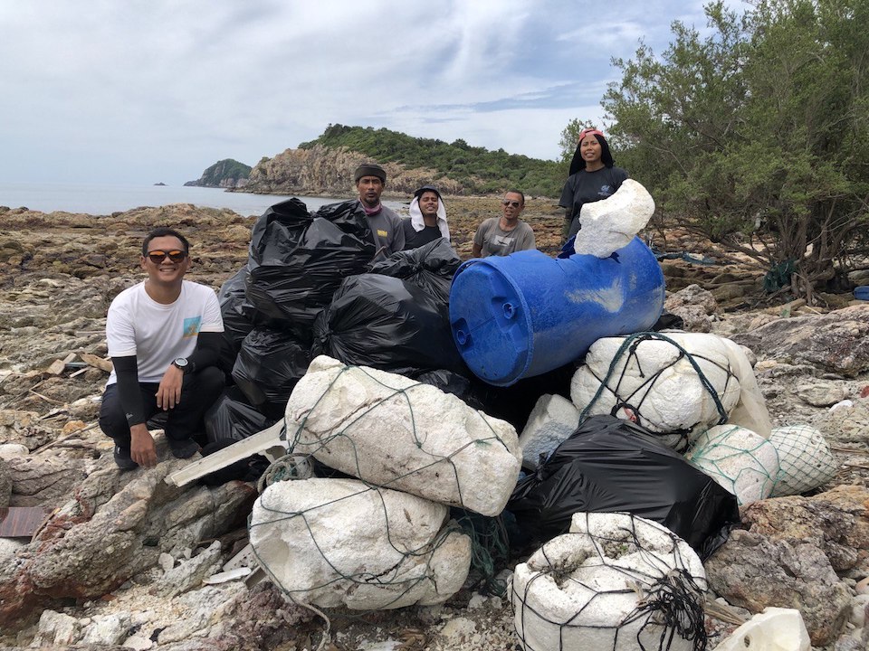 Nazirul posing with bags of a rubbish after a beach clean.