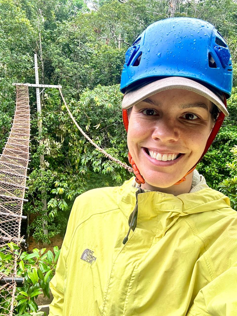 A woman wearing a blue hardhat in the field assessing roadkill mitigation sites.