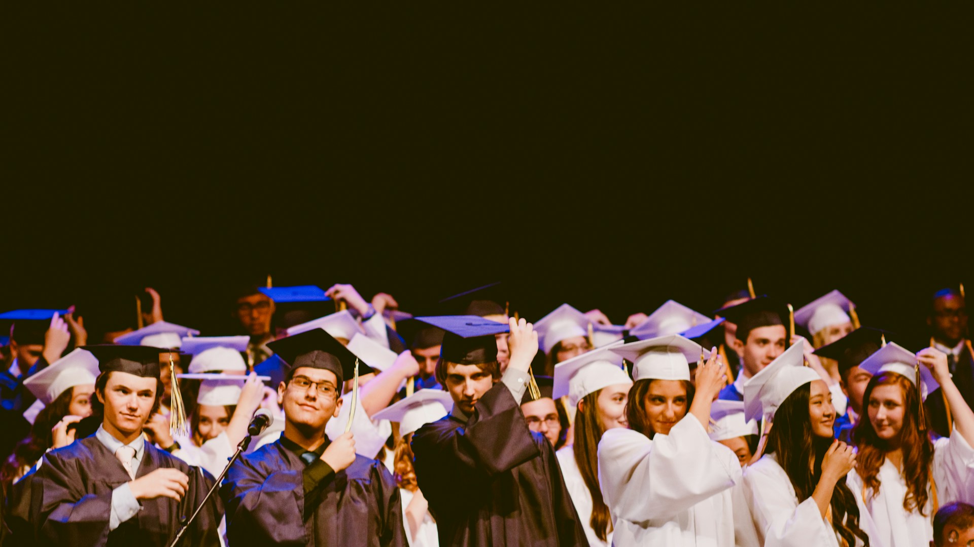 A group of gradutes wearing robes and hats against a black background. Whether or not you need a degree to work abroad in conservation depends on the type of job you're targetting.