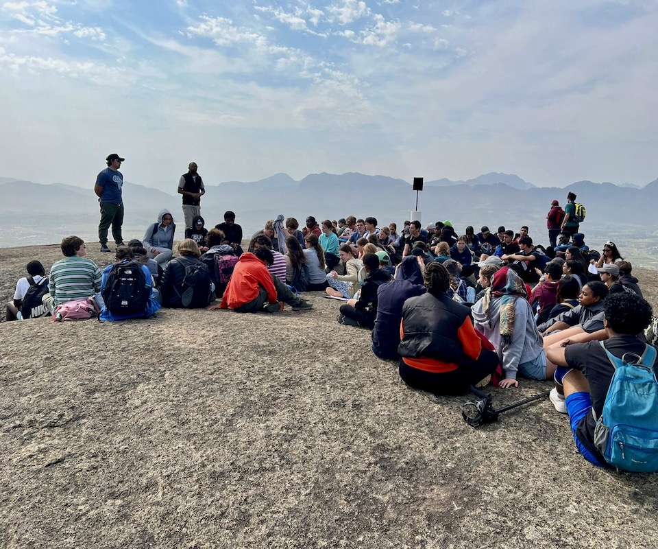 A male nature conservationist teaching a group outdoors.