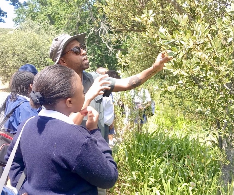 A male nature conservationist teaching students outdoors.
