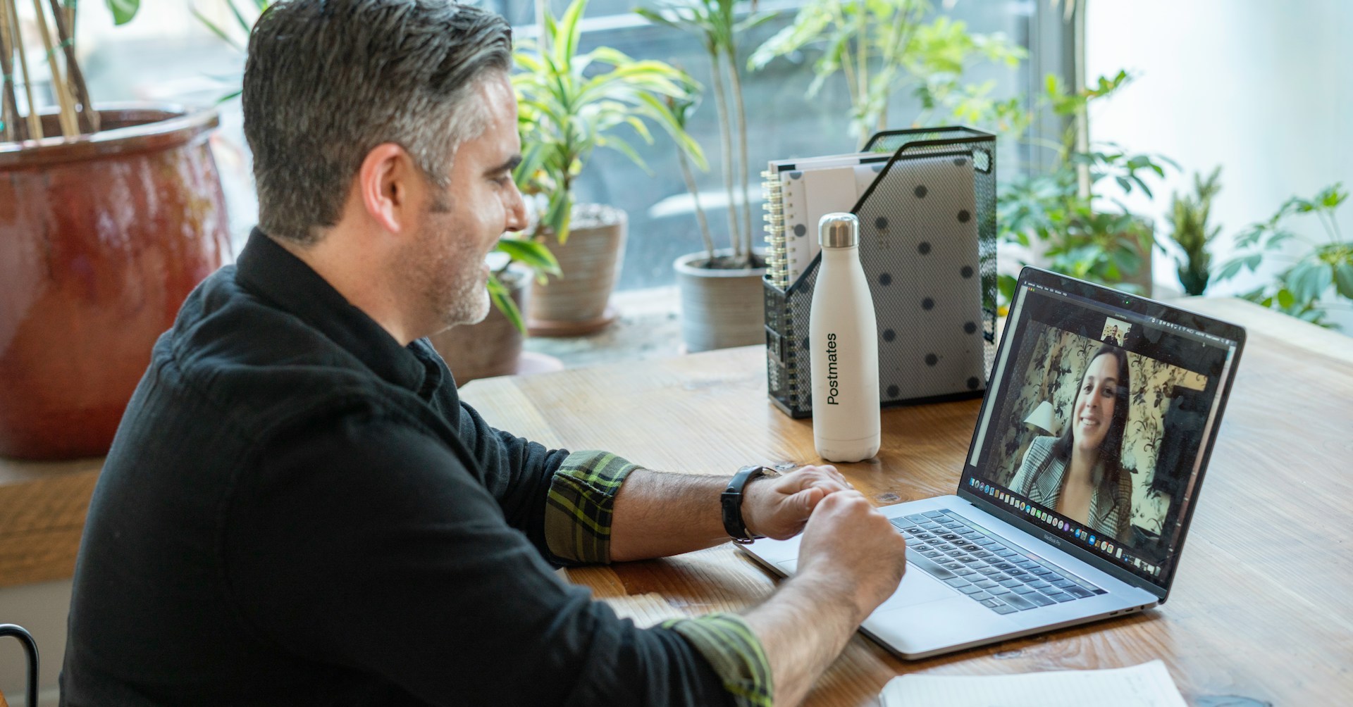 A man seated at a desk with a laptop in front of him, speaking to a woman on the screen. If you want to work abroad in conservation, you may need to practice your skills for online interviews.
