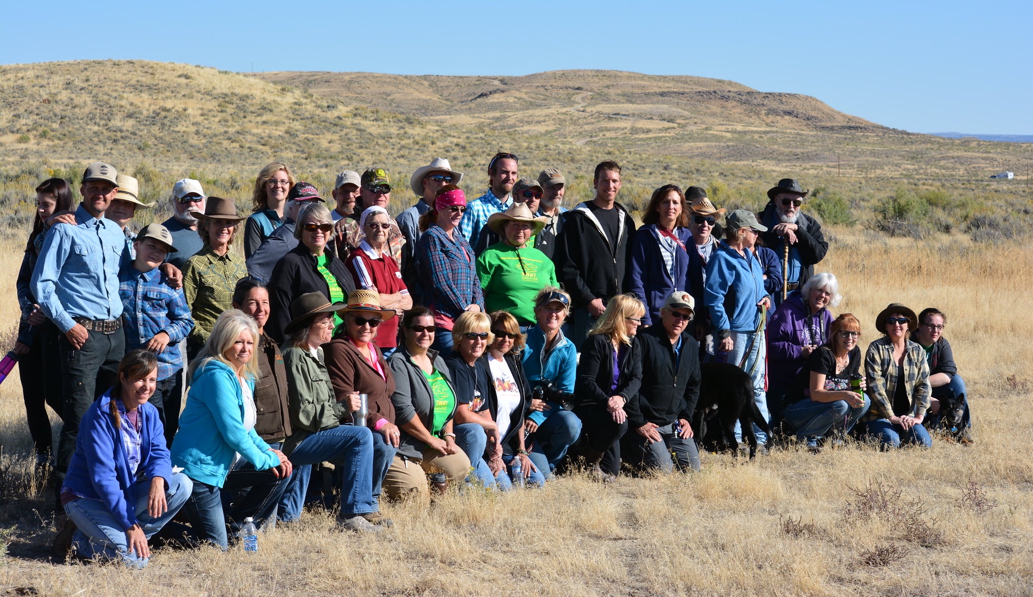 A large group of people posing for a photo in a dry, grassy landscape. Community-based conservation careers can be highly fulfilling when working alongside and in support of local people.